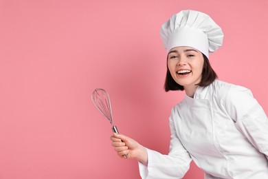 Happy confectioner with whisk on pink background, space for text
