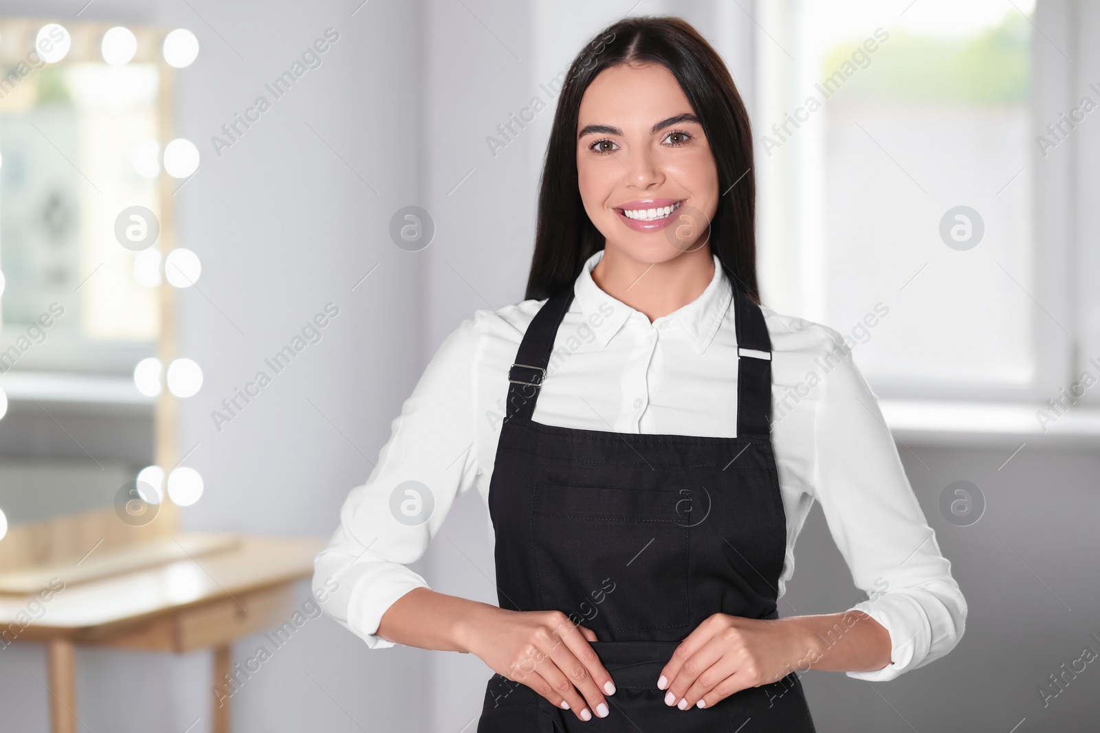 Photo of Portrait of professional hairdresser wearing black apron in beauty salon