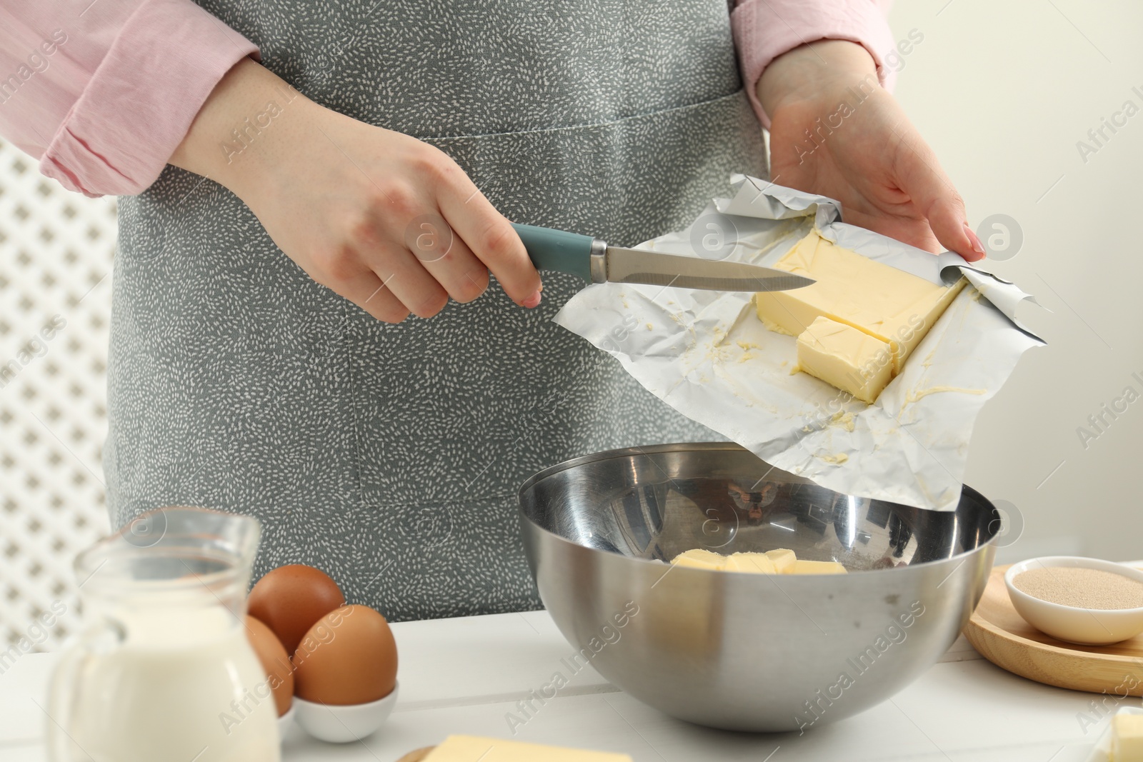 Photo of Woman adding fresh butter into bowl at white table, closeup