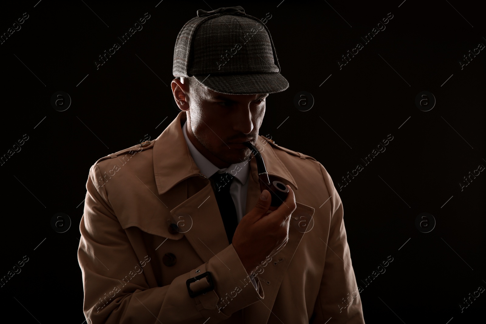 Photo of Old fashioned detective with smoking pipe on dark background