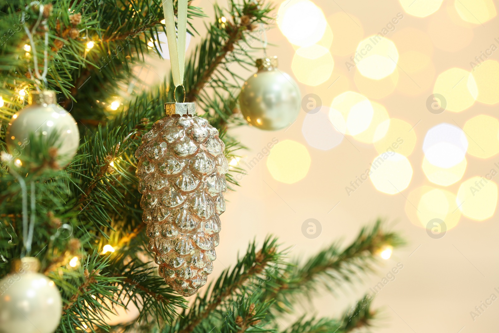 Photo of Cone shaped holiday bauble hanging on Christmas tree against blurred lights, closeup. Space for text