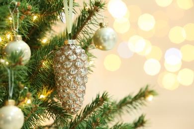 Photo of Cone shaped holiday bauble hanging on Christmas tree against blurred lights, closeup. Space for text