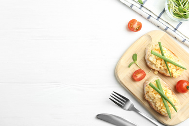 Tasty scrambled egg sandwiches served on white wooden table, flat lay. Space for text