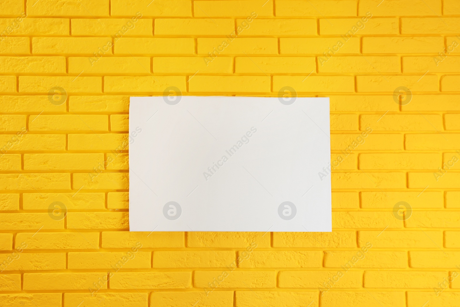 Photo of Blank canvas on yellow brick wall. Space for design