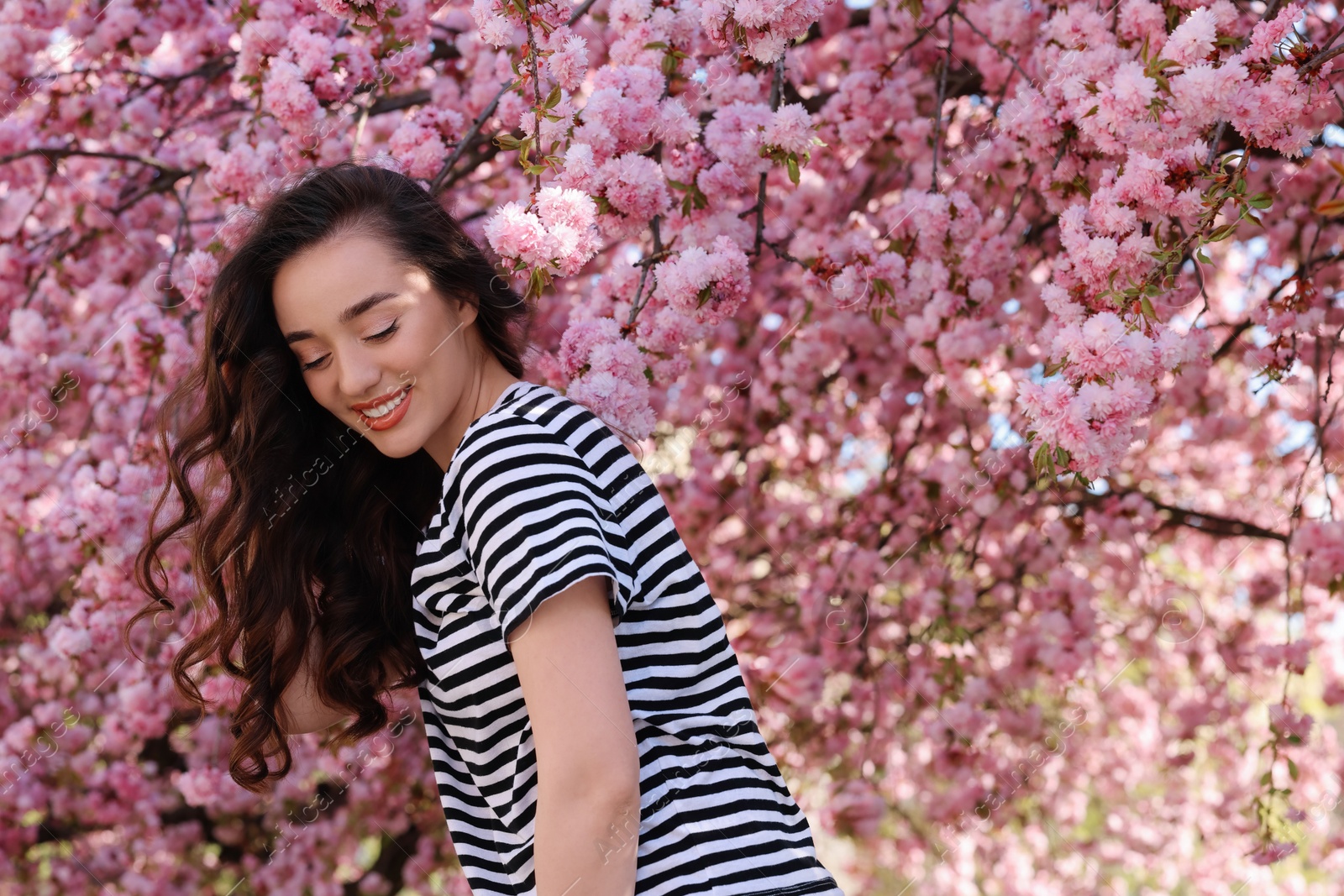 Photo of Beautiful woman near blossoming sakura tree on spring day