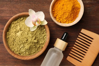 Photo of Comb, bottle with pipette, henna and turmeric powder on wooden table, flat lay