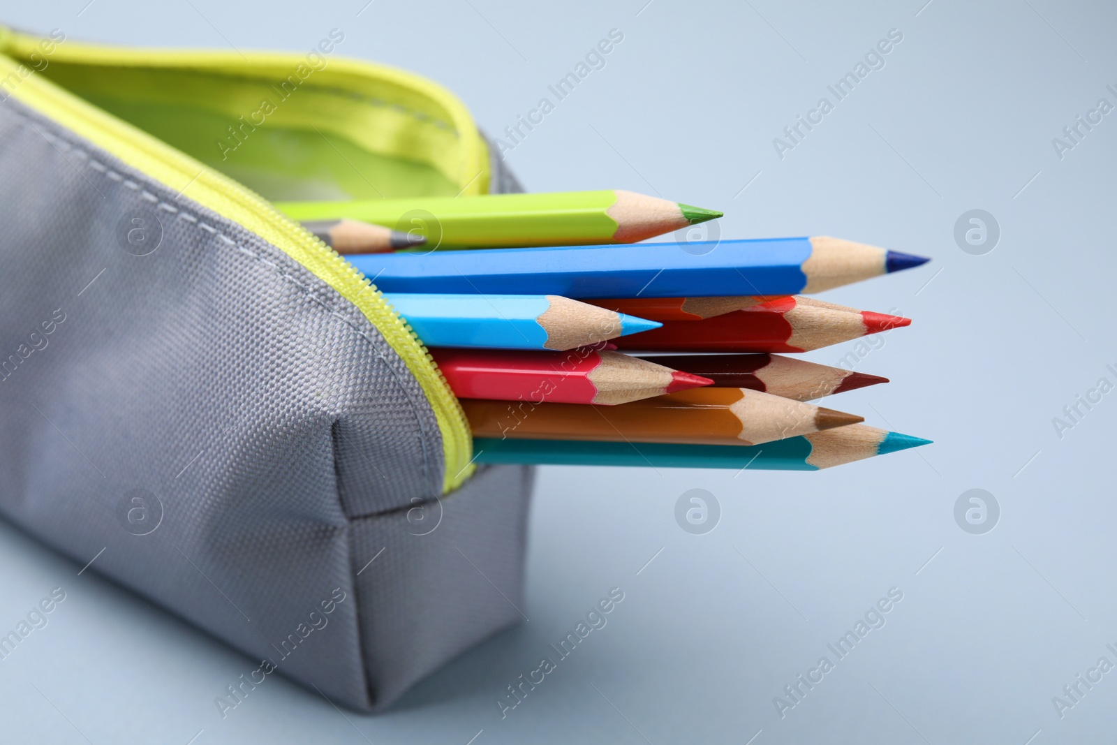 Photo of Many colorful pencils in pencil case on light grey background, closeup