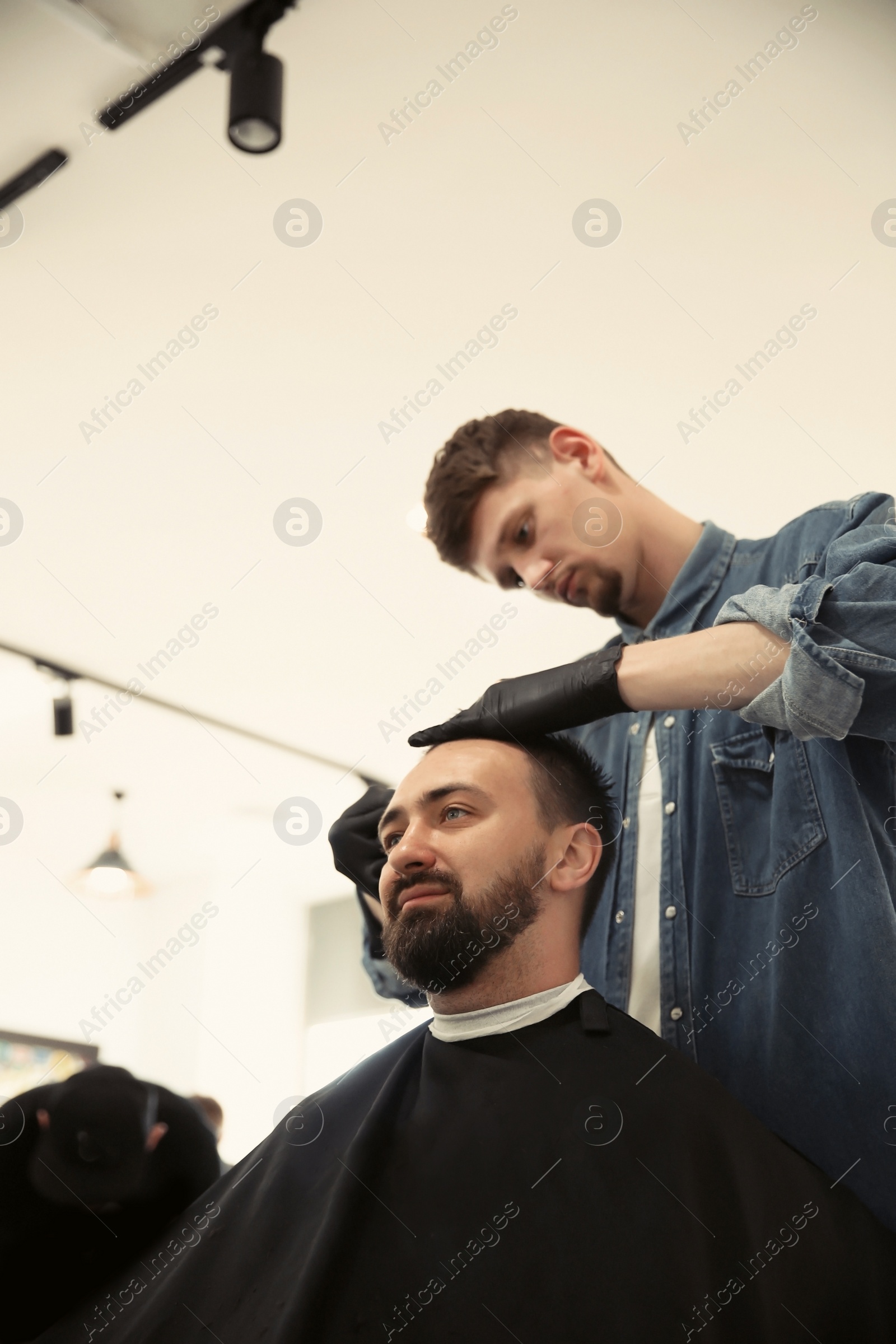 Photo of Professional barber working with client in hairdressing salon. Hipster fashion