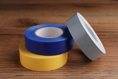 Colorful insulating tapes on wooden table, closeup