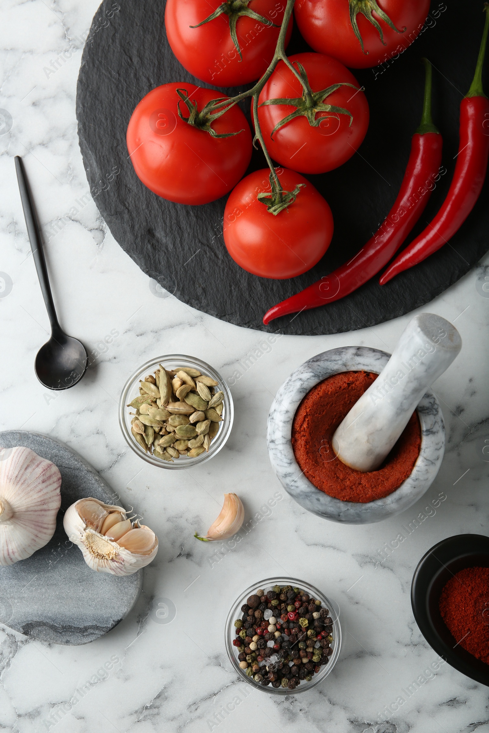 Photo of Mortar with red curry paste and ingredients on white marble table, flat lay