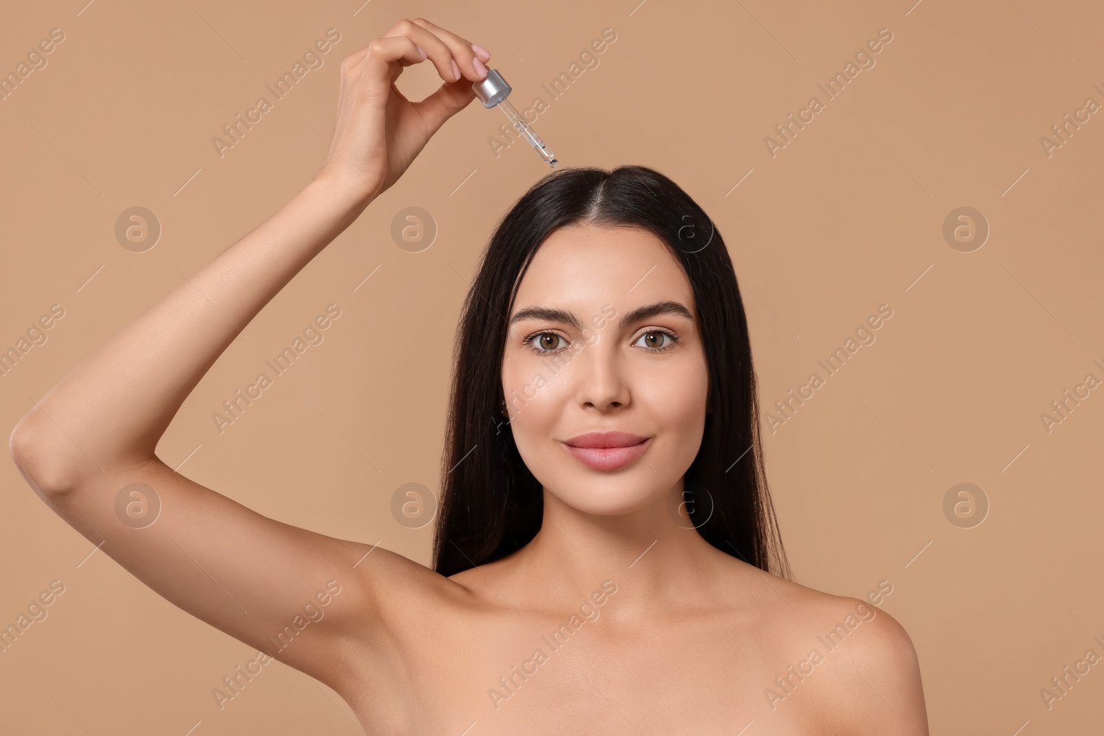 Photo of Beautiful woman applying hair serum on beige background. Cosmetic product