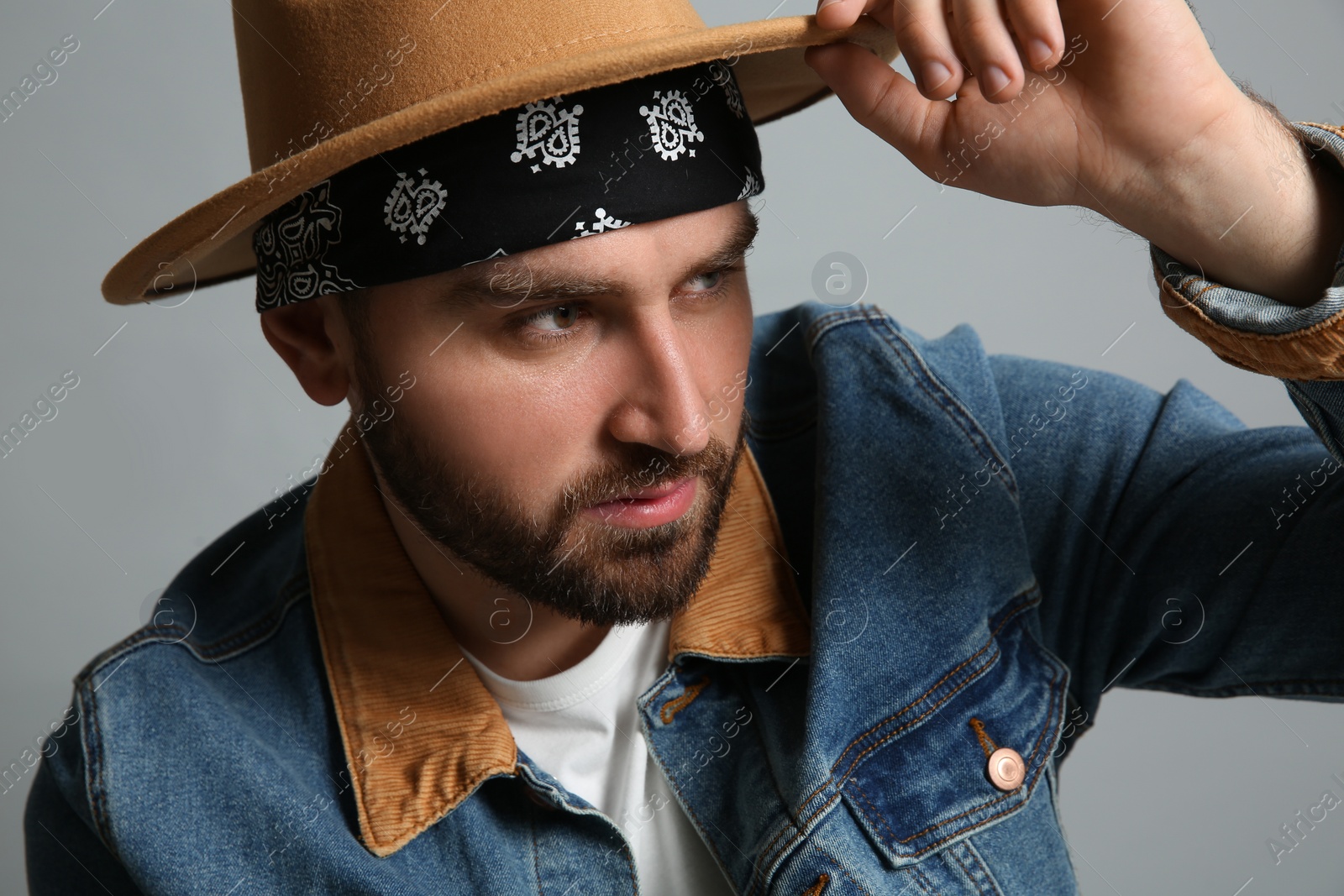 Photo of Fashionable young man in stylish outfit with bandana on grey background