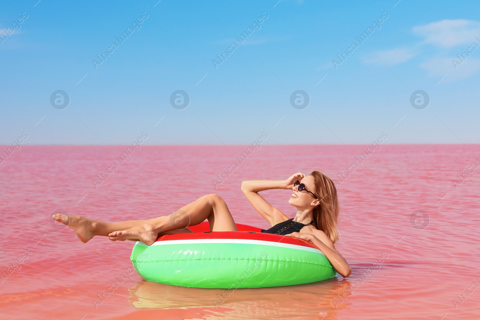 Photo of Beautiful woman on inflatable ring in pink lake