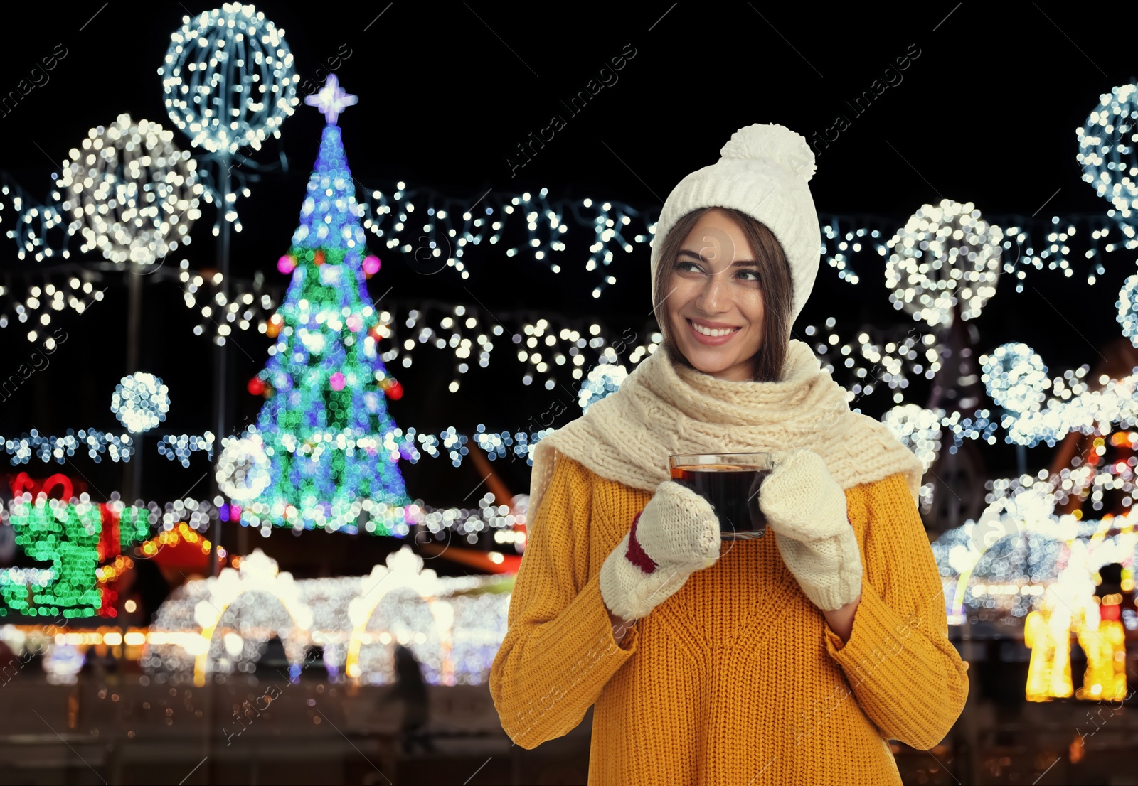 Image of Happy beautiful woman with cup of mulled wine at Christmas fair