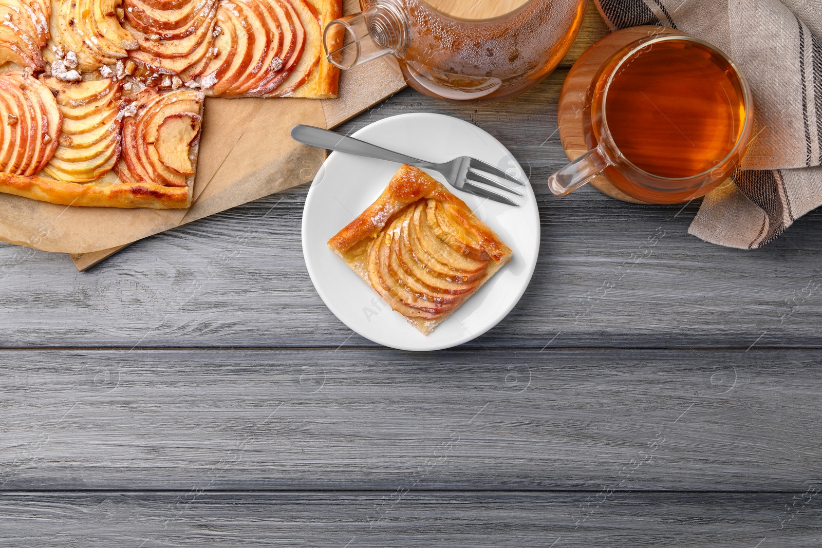 Photo of Tasty apple pie served with tea on grey wooden table, flat lay. Space for text