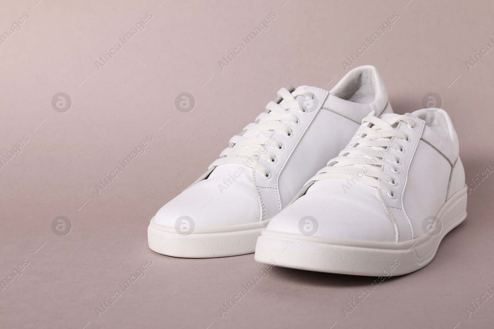 Photo of Pair of stylish white sneakers on grey background