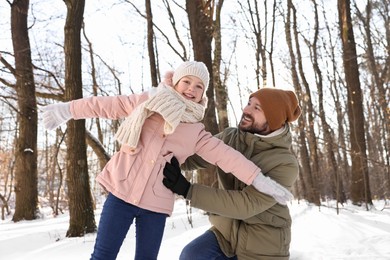 Family time. Happy father and his daughter in snowy forest