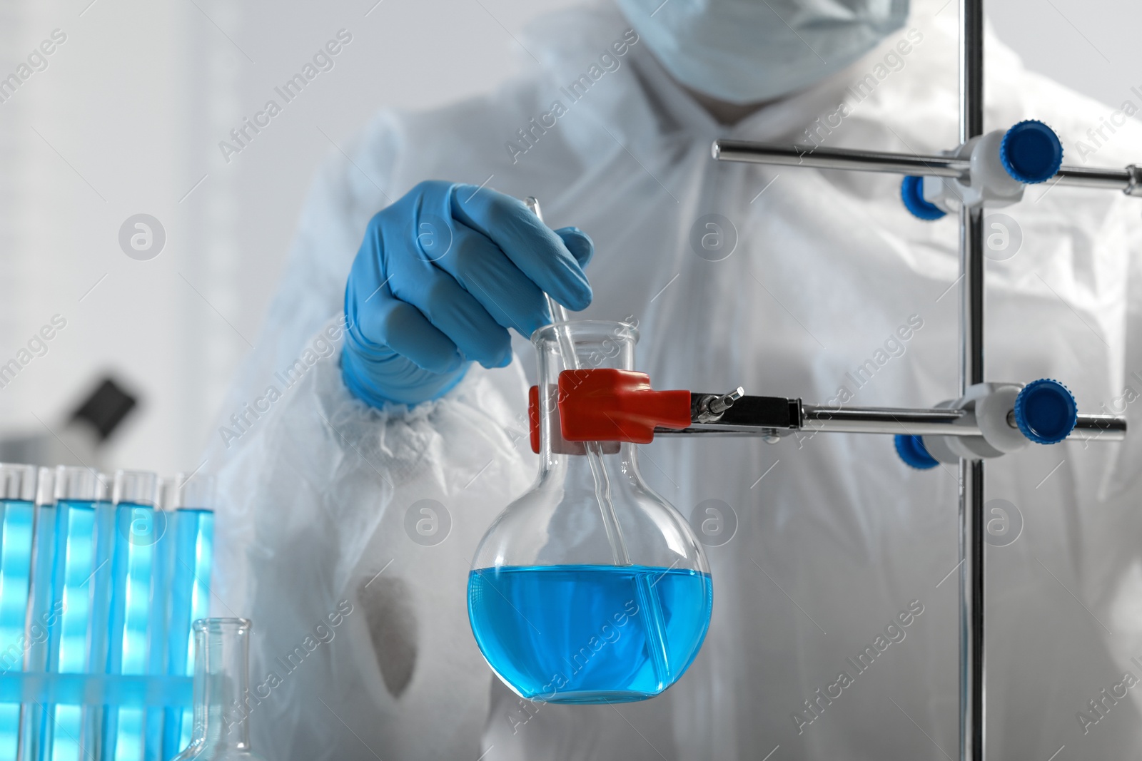 Photo of Scientist taking sample of light blue liquid in laboratory, closeup