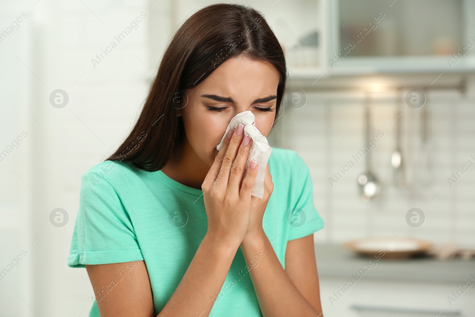 Photo of Young woman suffering from allergy in kitchen