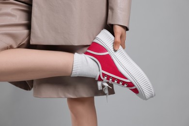 Photo of Woman posing in red classic old school sneakers on light gray background, closeup