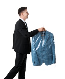 Young businessman holding hanger with jacket in plastic bag on white background. Dry-cleaning service