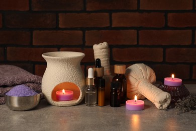 Photo of Aromatherapy. Scented candles and spa products on gray textured table