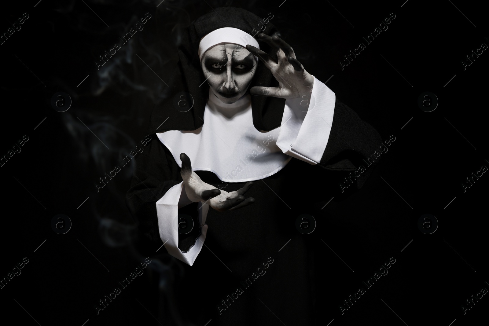 Photo of Portrait of scary devilish nun on black background. Halloween party look