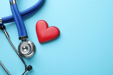 Stethoscope and red heart on light blue background, top view. Space for text