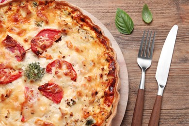 Photo of Tasty quiche with tomatoes and cheese served on wooden table, flat lay