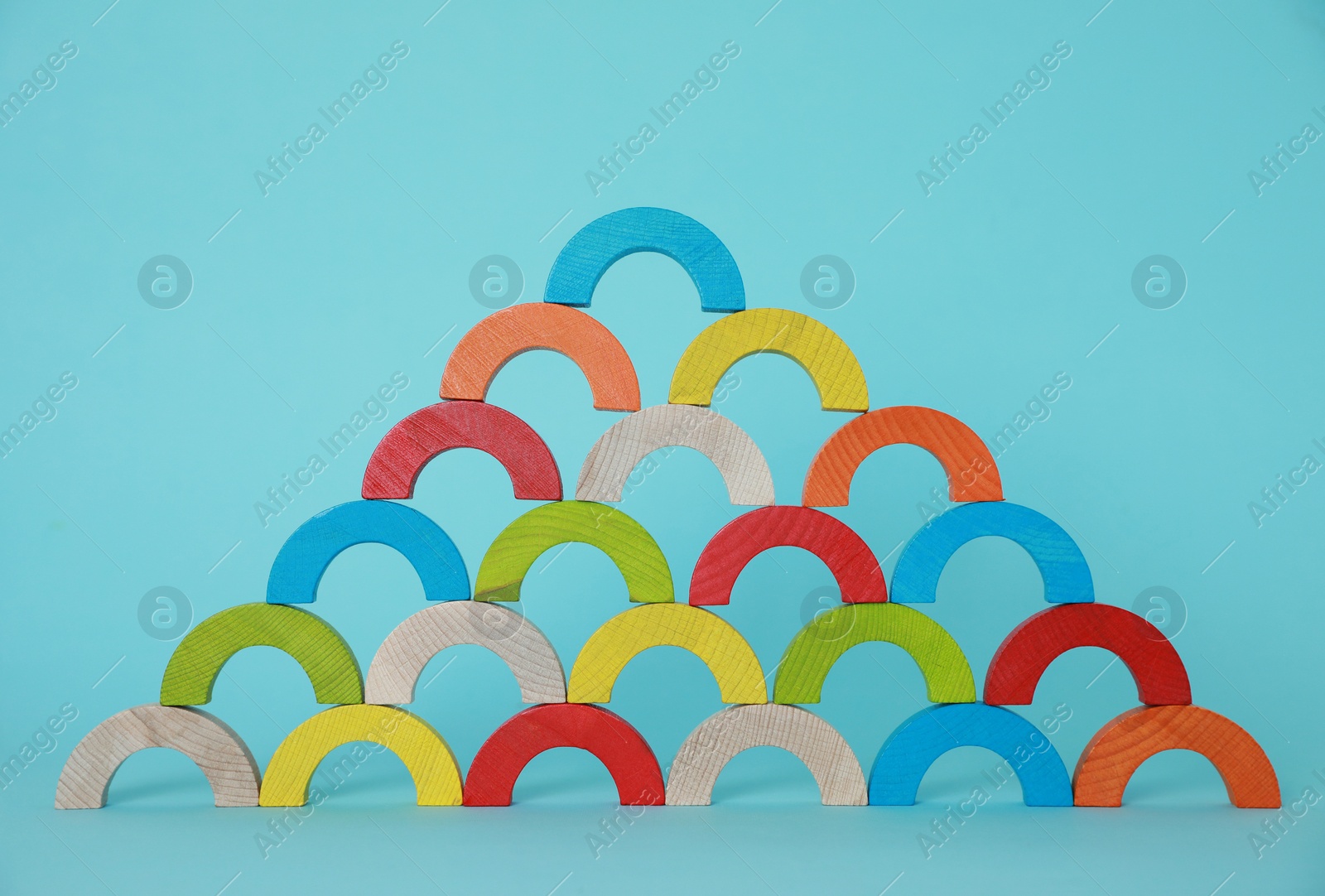 Photo of Colorful wooden pieces of playing set on light blue background. Educational toy for motor skills development