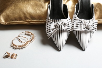 Photo of Pillow, lady's shoes and jewelry on light background, closeup