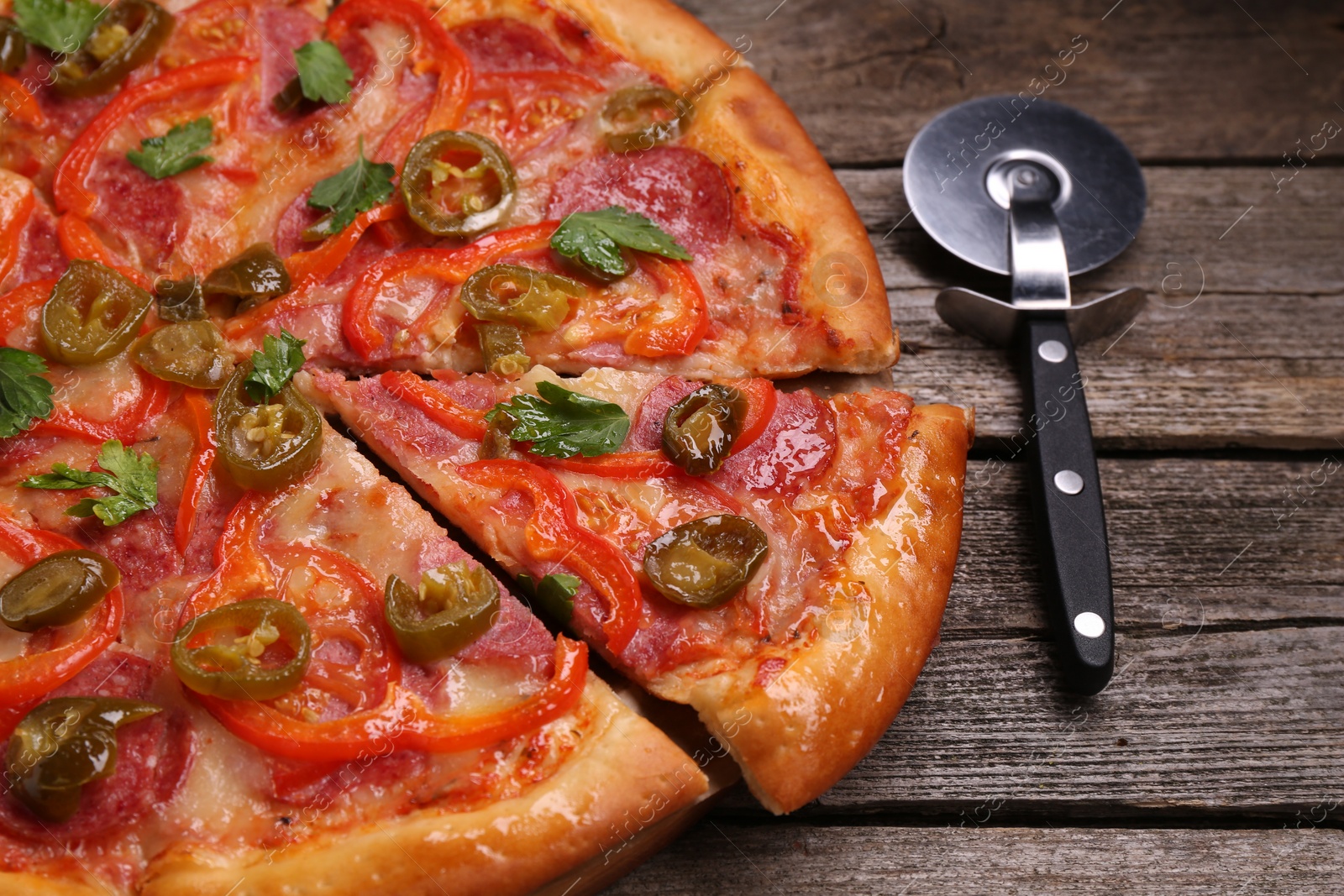 Photo of Delicious pizza Diablo and cutter on wooden table, closeup