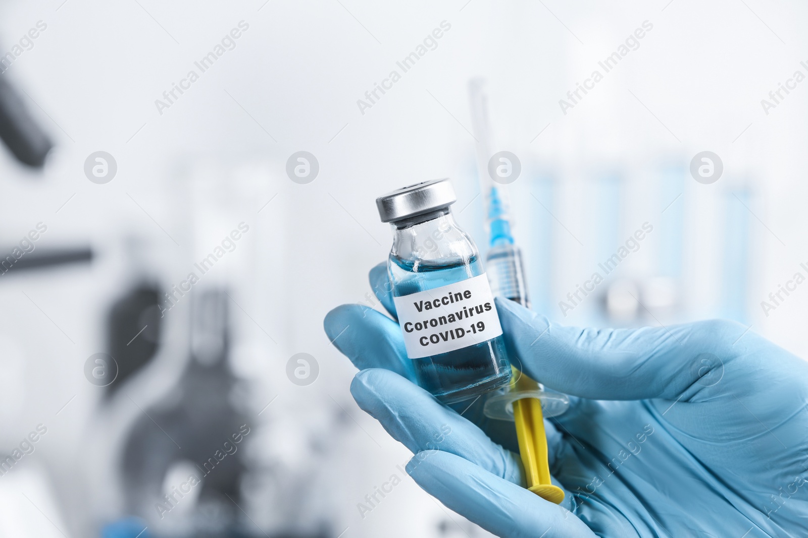 Image of Doctor holding coronavirus vaccine and syringe in laboratory, closeup