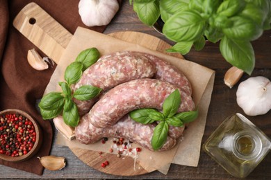 Photo of Raw homemade sausages and different products on wooden table, flat lay