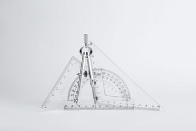 Photo of Triangle ruler, protractor and compass on white background