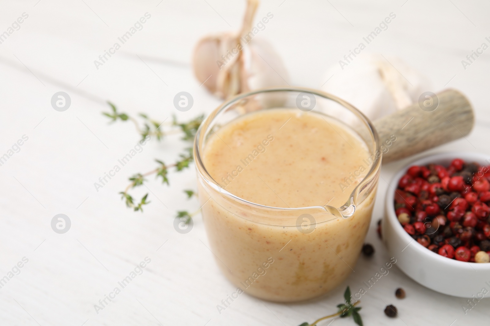 Photo of Delicious turkey gravy, thyme and peppercorns on white table, closeup. Space for text