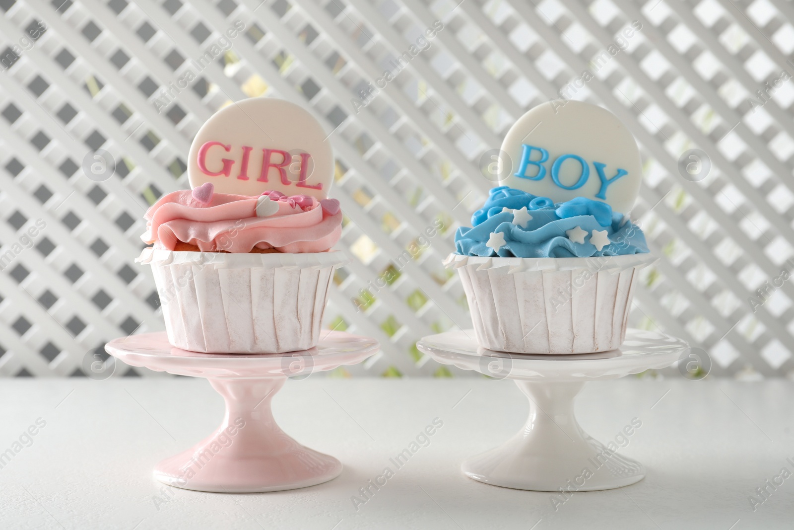 Photo of Delicious cupcakes decorated with Girl and Boy toppers for baby shower on white table