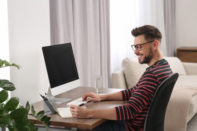 Photo of Online translation course. Man writing near computer at home