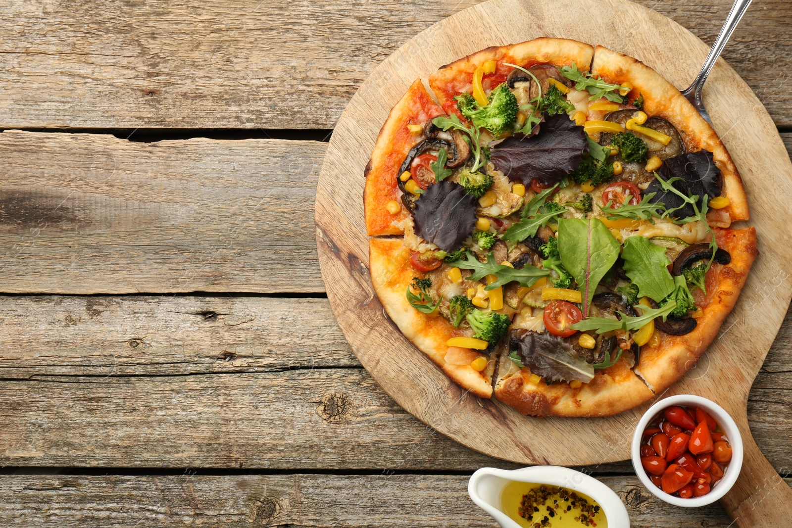 Photo of Delicious vegetarian pizza served on wooden table, top view. Space for text