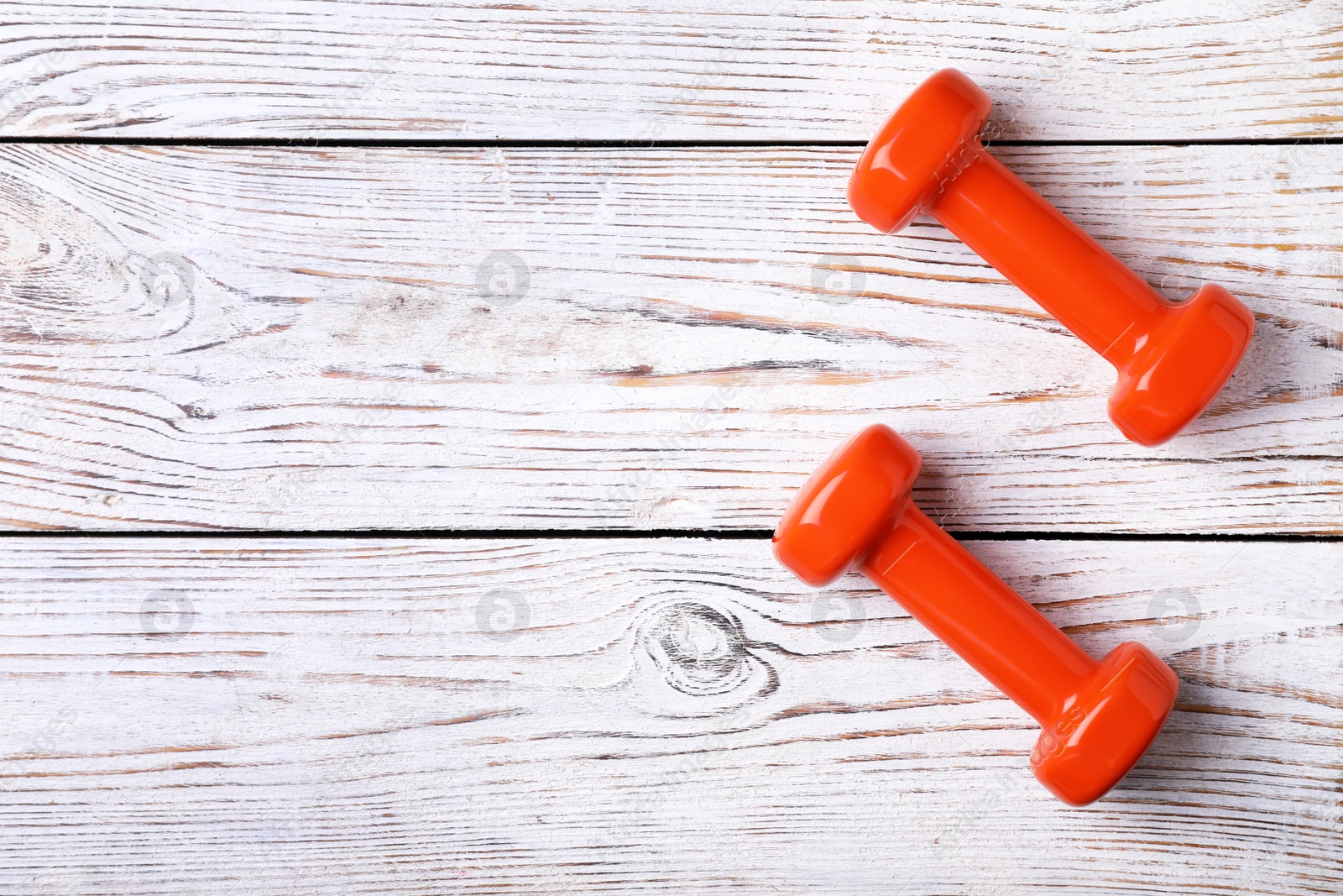 Photo of Bright dumbbells and space for text on wooden background, flat lay. Home fitness