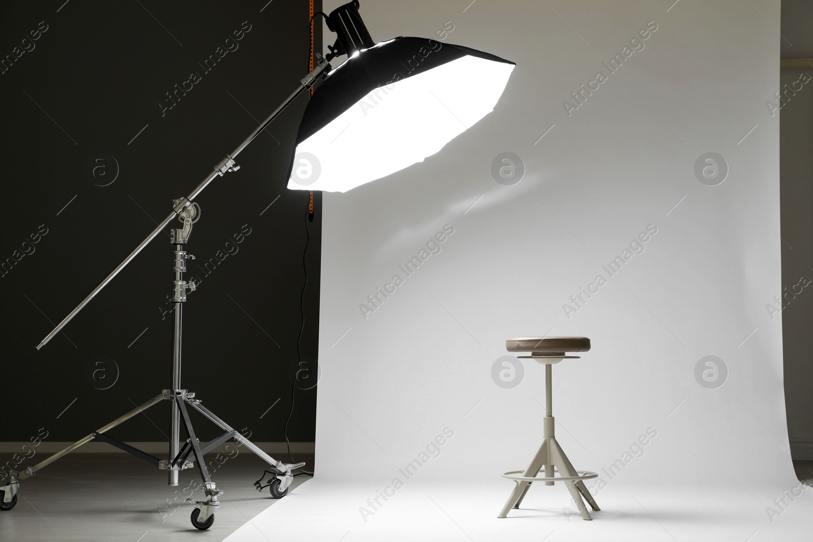 Photo of White photo background, stool and professional lighting equipment in modern studio