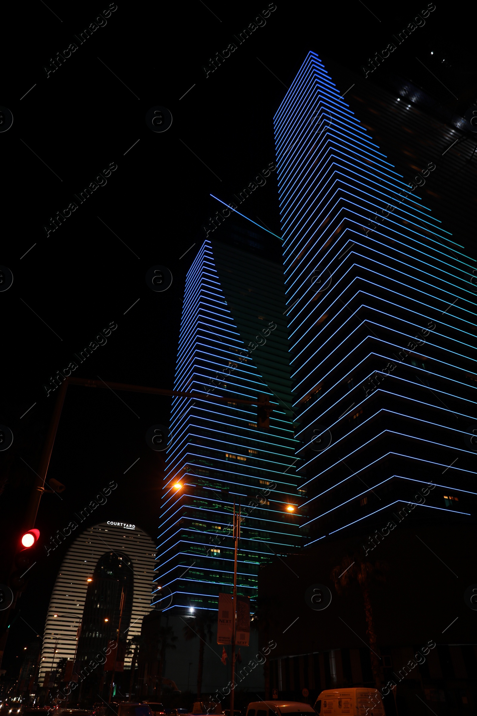 Photo of BATUMI, GEORGIA - JUNE 09, 2022: Night cityscape with illuminated buildings, low angle view