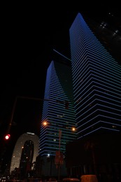 BATUMI, GEORGIA - JUNE 09, 2022: Night cityscape with illuminated buildings, low angle view