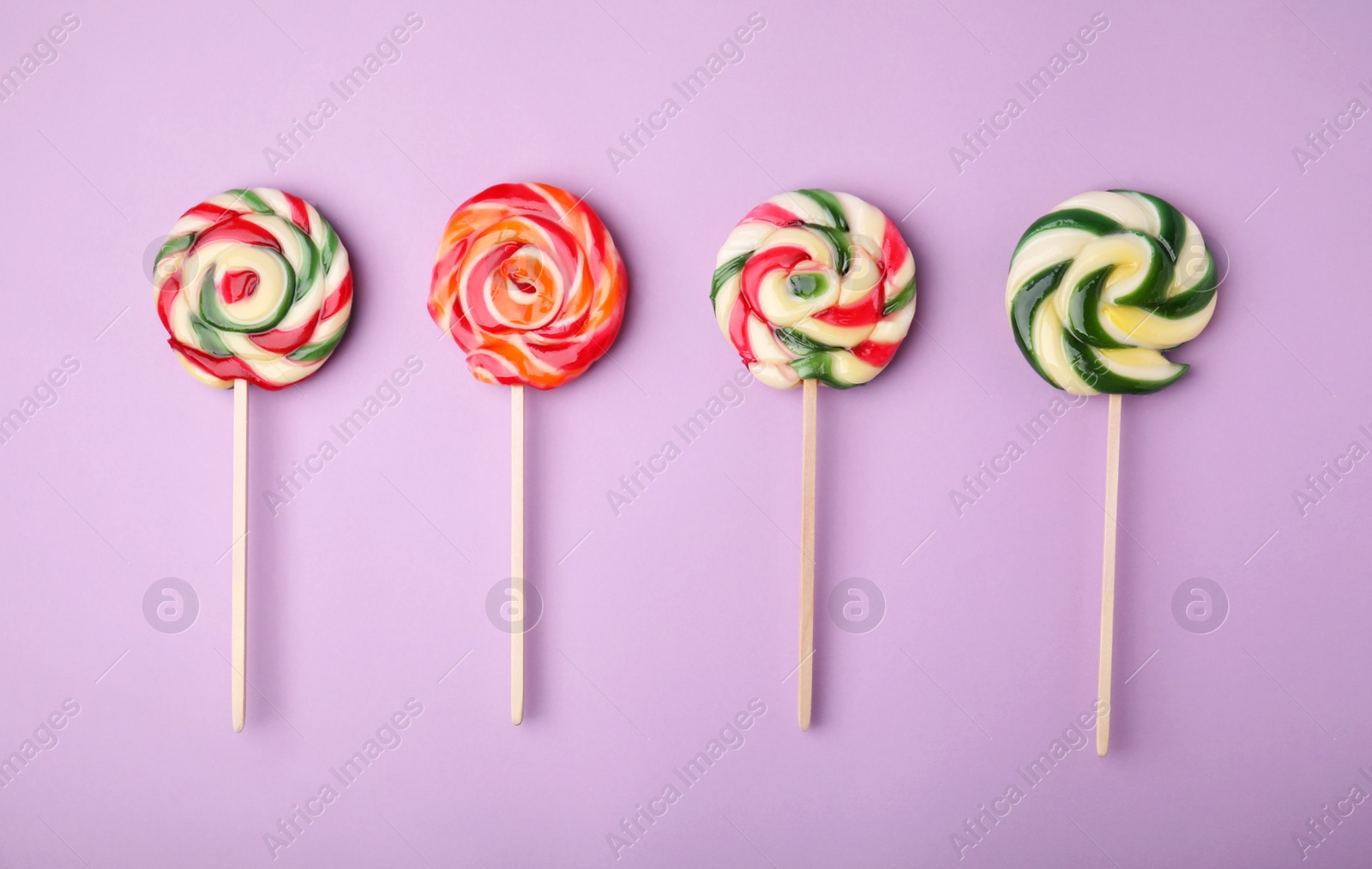 Photo of Many colorful lollipops on violet background, flat lay