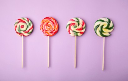 Photo of Many colorful lollipops on violet background, flat lay