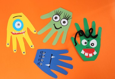 Funny hand shaped monsters on orange background, flat lay. Halloween decoration