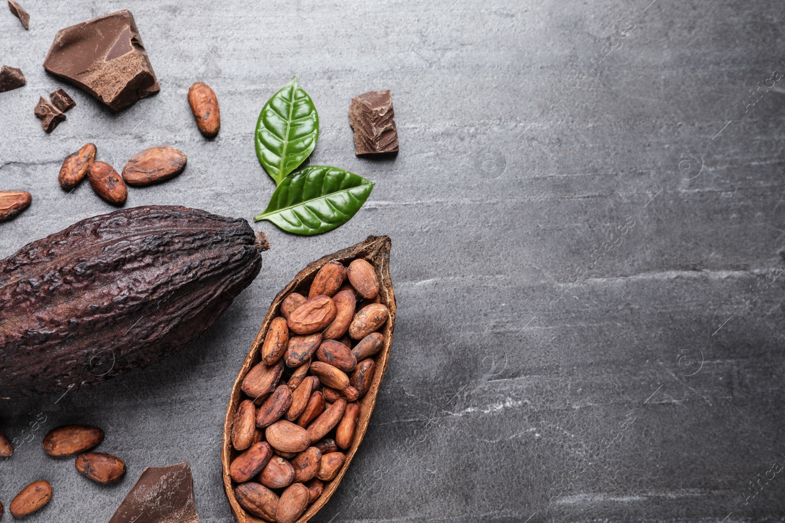 Photo of Flat lay composition with cocoa pods and chocolate on grey table. Space for text