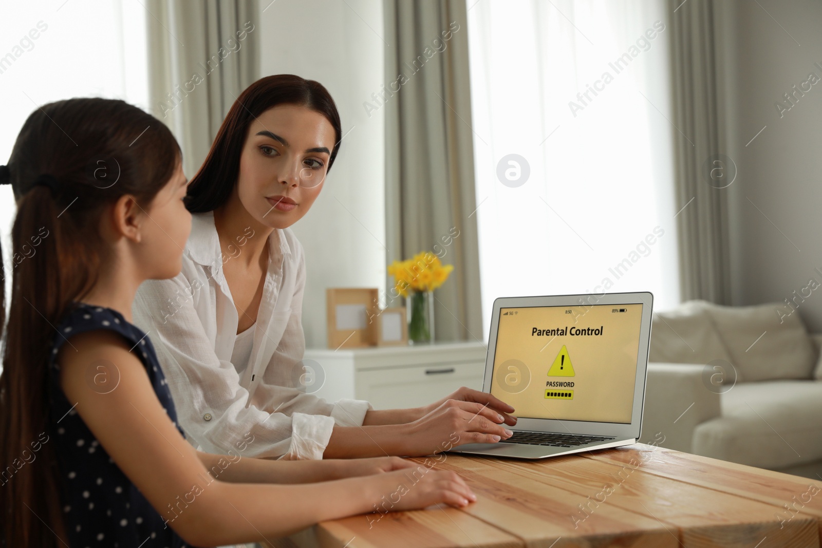 Photo of Mother installing parental control app on laptop to ensure her child's safety at home