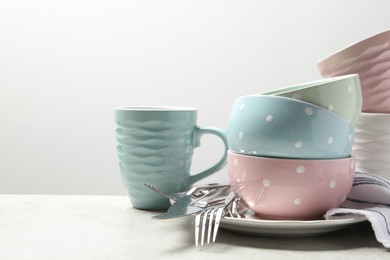 Beautiful ceramic dishware, cup and cutlery on light grey table