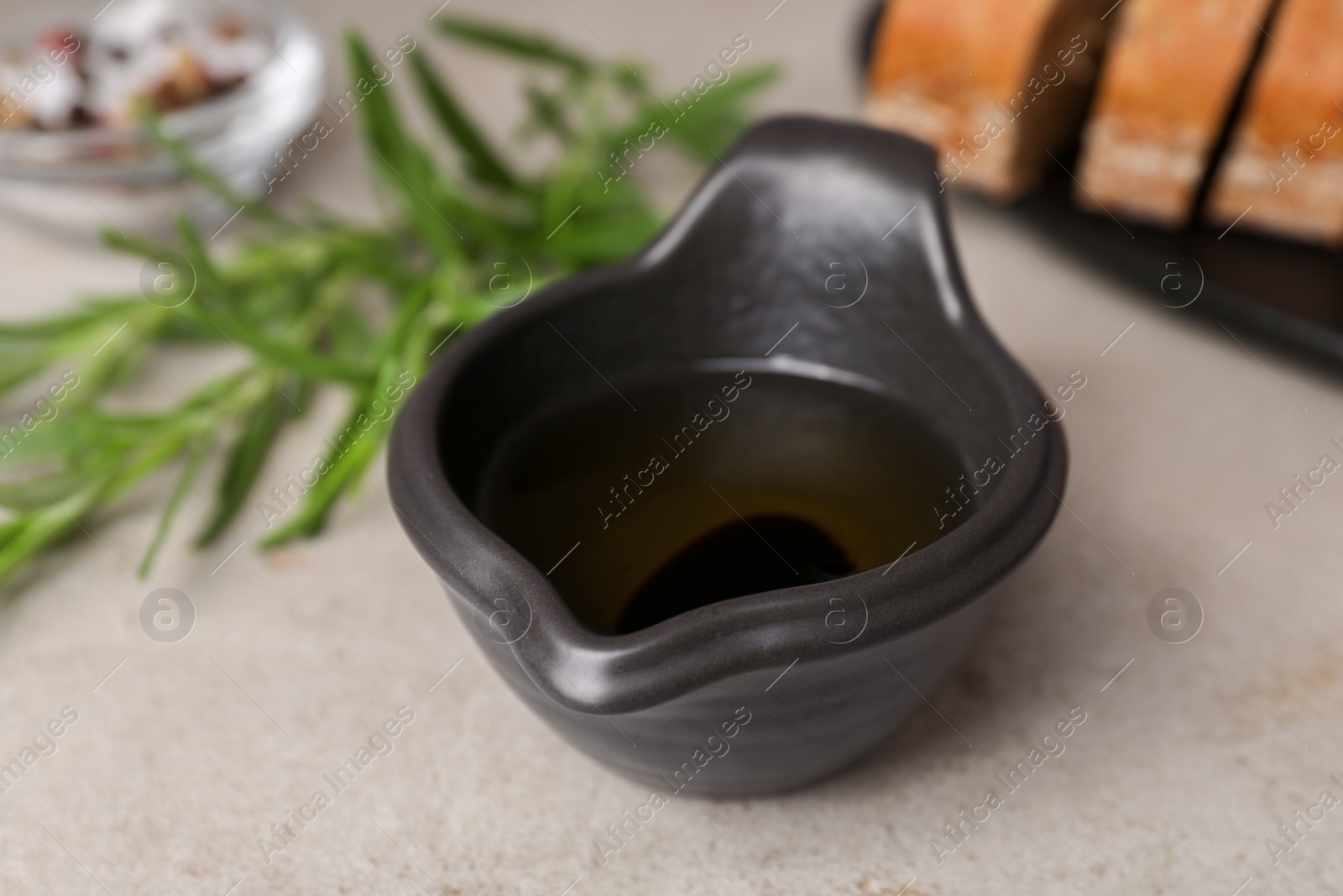 Photo of Saucepan of organic balsamic vinegar with oil on light grey table, closeup